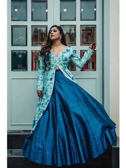 A powerful pose in a flowing blue lehenga and floral jacket. The upward angle and the movement in the skirt create a dramatic and high-fashion statement.