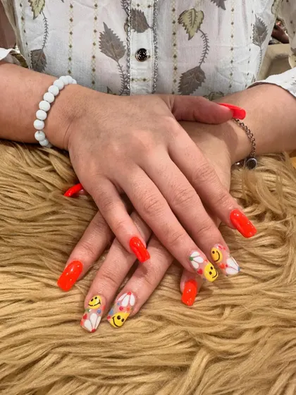 Fun and playful, this set of long, square-shaped acrylic extensions features bright red nails mixed with accent nails full of hand-painted smiley faces and daisies.
