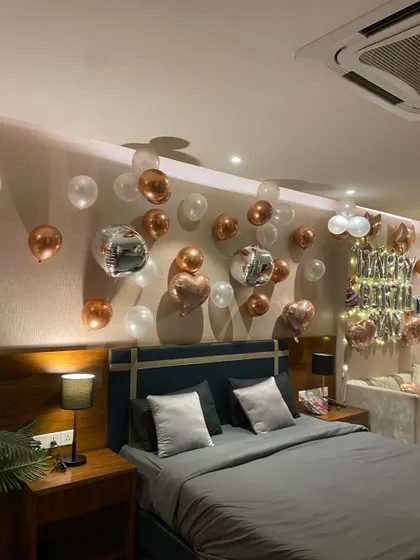 A wider view of the sophisticated birthday room setup, showing the "Happy Birthday" foil balloons and fairy lights.
