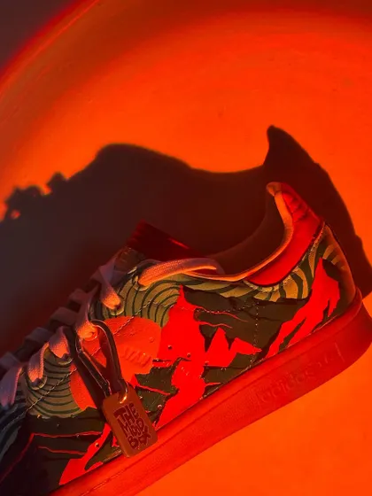 Another dramatic shot of the trippy Stan Smiths under an orange light.