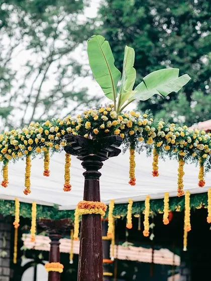 A mandap decorated for a Muhurtham ceremony with traditional yellow marigold garlands and banana leaf accents, creating a classic South Indian look.