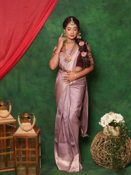 An elegant and captivating Muhurtham look. The soft lilac saree is complemented by a subtle pink and purple smokey eye, a messy floral braid, and stunning temple jewellery with green and pink stones.