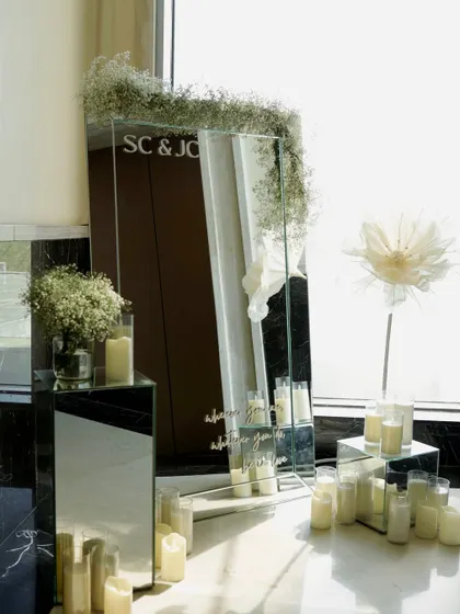 A personalized mirror sign with the couple's initials, surrounded by baby's breath and candles, serves as an elegant welcome piece.