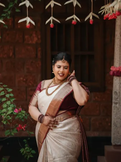 A graceful portrait of the bride in her elegant white and maroon saree, showcasing her traditional wedding look.