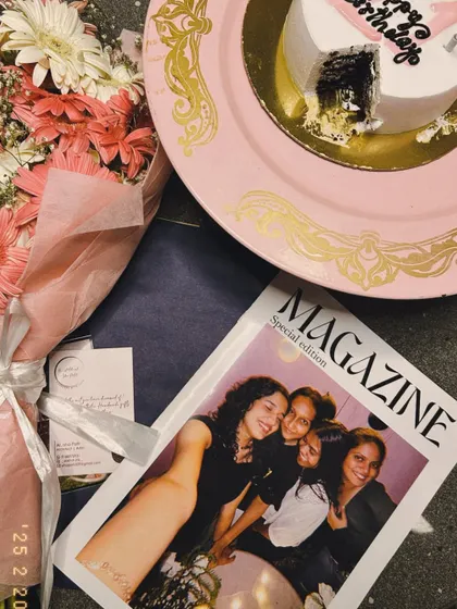 A flat lay of a birthday celebration, featuring the custom friendship magazine alongside a cake and a bouquet of flowers. It’s all about making someone feel loved.
