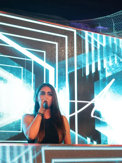 A powerful shot of me on the mic against a backdrop of futuristic blue and white graphics. I use the microphone to connect, guide, and energize the crowd throughout my set.