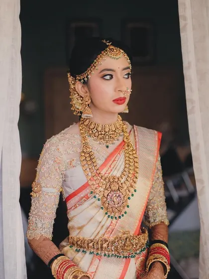 This bride is the epitome of grace in her off-white Kanchivaram saree. The custom blouse is fully embroidered with gold thread, creating a look of timeless elegance.