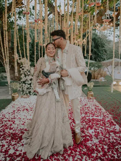 A complete family portrait, including the furry member. The couple and their dog pose together after the Varmala, a heartwarming and personal touch.