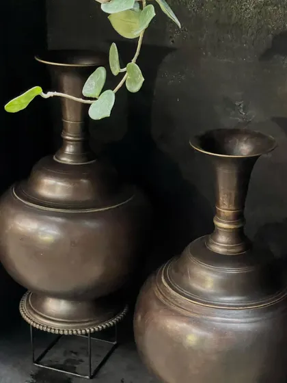 The pair of large copper vases, one on a stand and one on the floor. This arrangement shows their versatility and how they can bring symmetry and style to an entryway or corner.