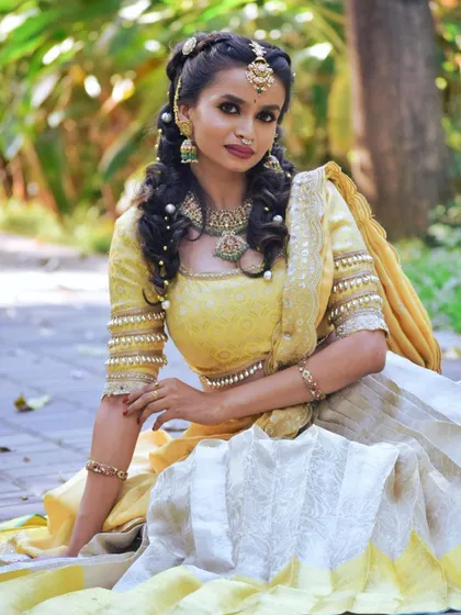 This bride is styled in a beautiful yellow and white lehenga, her look completed with a unique Jadau set with pearl detailing in her hair.