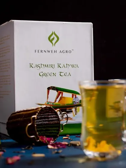 The final styled shot of the Kashmiri Kahwa, ready to be served. The composition is balanced to be both beautiful and informative, showing the product, its packaging, and the final result.