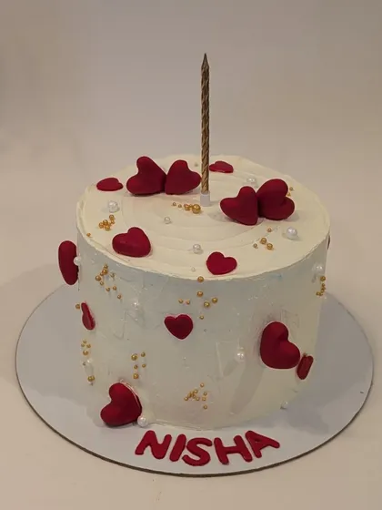 A simple white cake adorned with little red fondant hearts. The single gold candle makes it perfect for an intimate birthday or anniversary celebration.