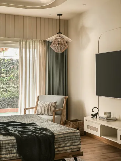 Light becomes poetry in this bedroom corner, where a tiered rattan pendant casts intricate shadows. A custom pelmet with vertical grooves orchestrates the layered curtains, adding a touch of architectural music.