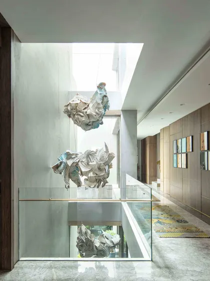 The 'Radha Krishna Raas Leela' installation, a collaboration with artist Ankon Mitra, viewed from a different angle. This perspective highlights how the folded forms, inspired by Shibori dyeing, create a divine dance of space and form within the atrium.
