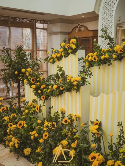 A beautiful backdrop of yellow and white stripes adorned with cascading sunflowers, creating a perfect photo wall for the Haldi ceremony.