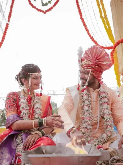 A candid moment during a Maharashtrian wedding ceremony. The bride and groom share a smile, seated at the holy fire, their connection evident even during the rituals.