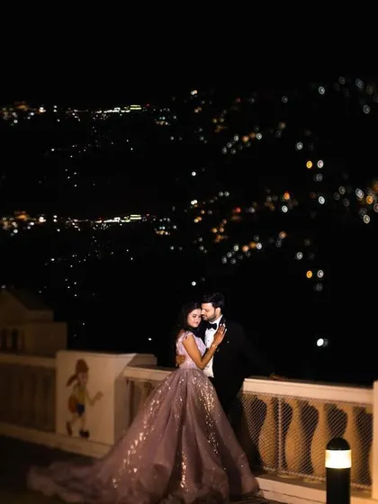 A romantic night-time portrait of a couple against the sparkling city lights of Mussoorie. We use professional lighting techniques to create magical, high-quality images even after the sun goes down.
