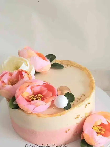 This lovely floral cake is made with no fondant, featuring a soft pink and white ombre buttercream finish. It's adorned with beautiful pink peonies for a fresh and pretty look.