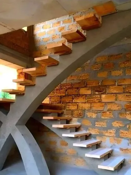 This image shows a unique staircase under construction, featuring floating wooden treads anchored into a raw brick and concrete wall. It's a great example of combining rustic materials with a modern design concept.