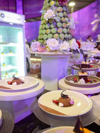 A dessert station featuring a beautiful macaron tower adorned with fresh flowers, alongside individually plated chocolate mousses.