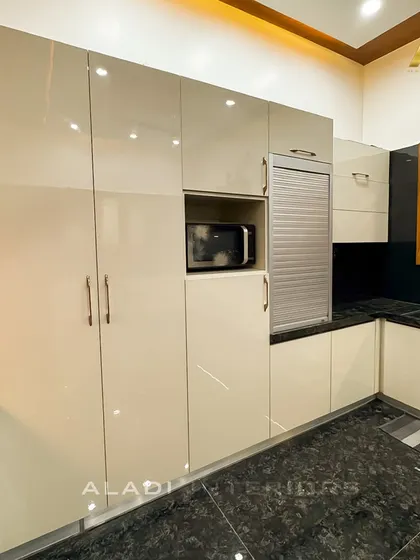 This image showcases the tall storage unit in the kitchen, with a built-in microwave and a rolling shutter cabinet for appliances, keeping the countertop clutter-free.