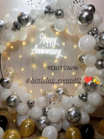 A sophisticated and elegant anniversary backdrop. This setup features a mix of white, silver, and confetti-filled balloons on a circular frame, with a delicate "Happy Anniversary" neon sign providing a beautiful focal point.