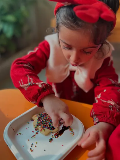 A child adds sprinkles to her cookie, a classic and joyful part of any festive baking activity.