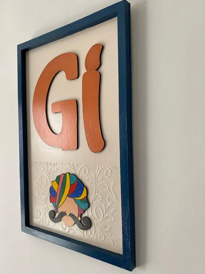 A side view of the framed house number plate, showing the depth of the wooden letters and the textured background.