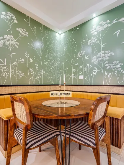 We transformed this compact dining area by creating an L-shaped bench with built-in storage. The hand-painted green and white mural, contrasted with bright yellow fabric, adds a vibrant yet sophisticated touch.