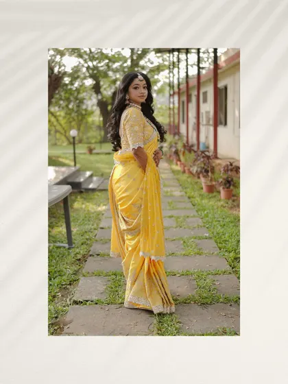 A full-length portrait showcasing the bride's elegant yellow saree. The pathway and the greenery of the farm venue provide a simple yet beautiful setting for this graceful shot.