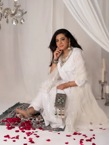 Beautiful in white. This portrait has a dreamy, ethereal quality, with the sheer curtains and scattered rose petals adding to the romantic and serene mood.