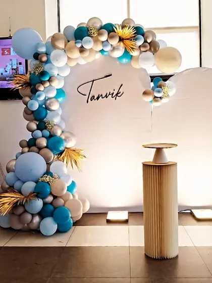 A classy and elegant coustamised decoration for Tanvik's naming ceremony. This modern setup features a blue, white, and gold balloon arch and "BABY" blocks for a stylish celebration.