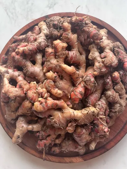 A wooden plate filled with local red ginger. Its unique aroma and potent flavor are indispensable in our kitchen for creating authentic Naga curries and chutneys.