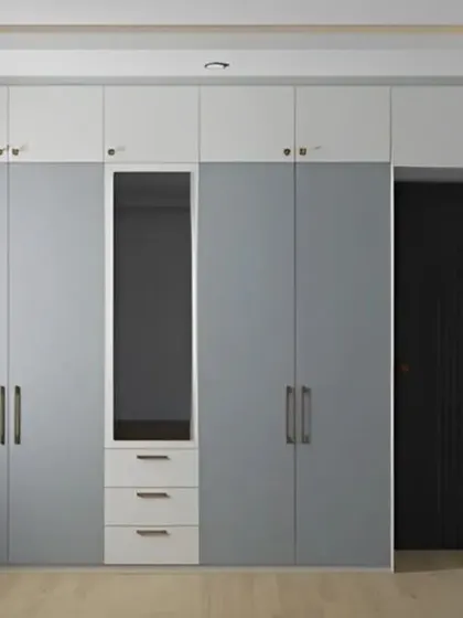 This floor-to-ceiling wardrobe in a calming grey and white palette offers immense storage. The design includes a built-in dressing mirror, making it a highly functional addition to the bedroom.