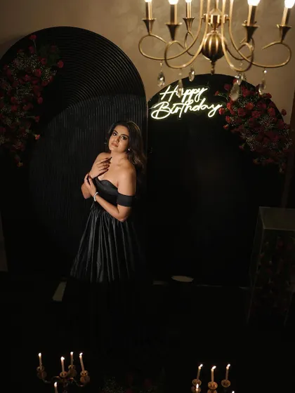 Another perspective of the chic adult birthday photo corner, with the warm glow of the chandelier and neon sign contrasting with the dark, sophisticated decor.