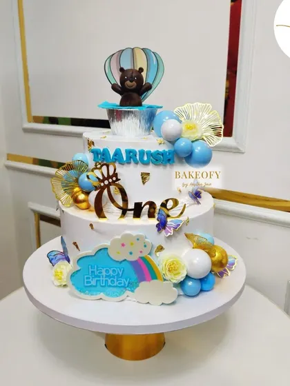 The full view of the two-tier hot air balloon cake for Taarush's first birthday. The design includes a rainbow and clouds for an extra touch of sweetness.