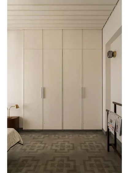 A bedroom in Apartment 1005, showing the minimalist wardrobe and the patterned cement tile floor.