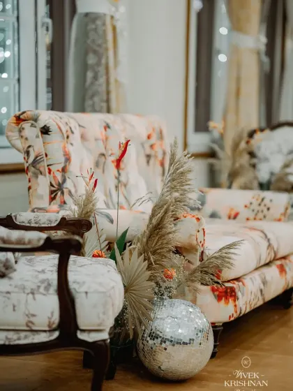 A cozy corner with floral print furniture and a disco ball adds a touch of vintage glamour to the reception decor.