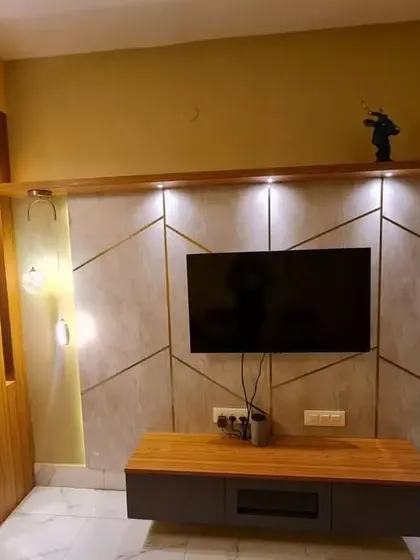 Another angle of the Kolkata living room, focusing on the custom TV unit with its unique geometric design and ambient lighting.