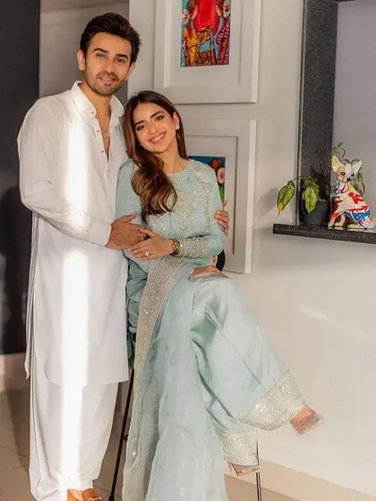 A simple and elegant coordinated look. Her pastel blue suit with silver embroidery is complemented by his classic white pathani suit, perfect for a daytime event or puja.