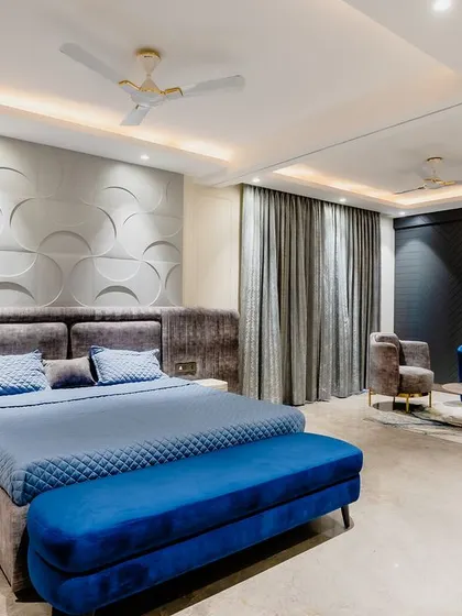 The full bedroom includes a separate seating area with a plush blue sofa, making it a complete master suite.