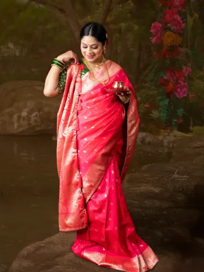A beautiful portrait set against a painted natural scene. The mom-to-be, in a vibrant pink saree, looks like a figure from a classic Indian painting.