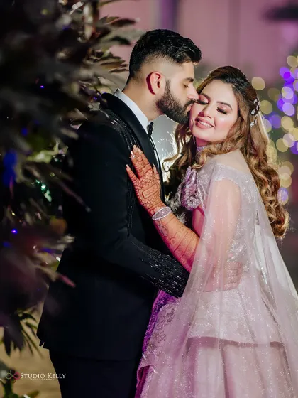 A tender moment with the groom kissing his bride's cheek, captured in the soft light of their reception.