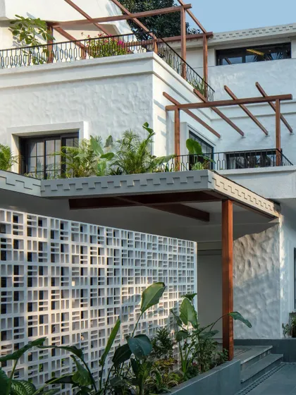 The facade of Summer Haus, as seen in Elle Decor. The design incorporates a breeze block wall and wooden pergolas to add texture and architectural interest to the exterior.