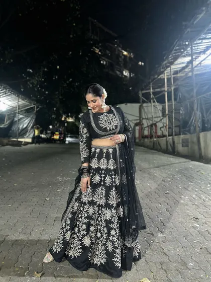 A full-length shot of Donam Bajwa in her festive black lehenga, showing how a rented outfit can make you shine during the holiday season.