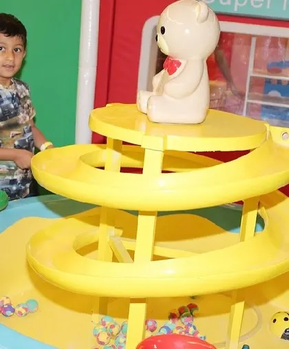 A young child plays with a spiral ball drop toy in our dedicated toddler area.