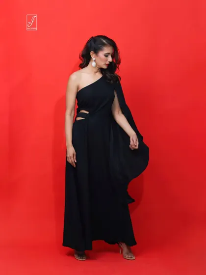 A full-length view of the black gown, showcasing the thigh-high slit and the elegant drape of the single long sleeve.