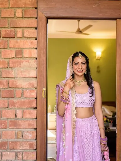 The bride, fully ready, peeking out of her room with a happy smile.