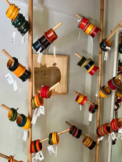 Our lightweight Channapatna bangles make a sweet wooden sound when worn. This display at our store showcases the variety of colors and designs available, each set a small piece of wearable art.