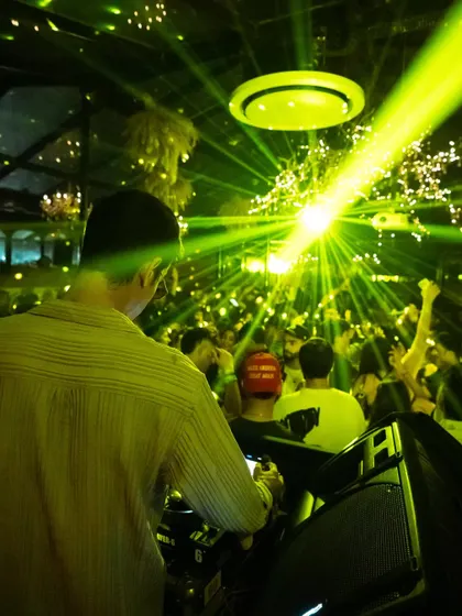 The view from behind as the green lasers cut through the crowd during a peak-time Afro House set.